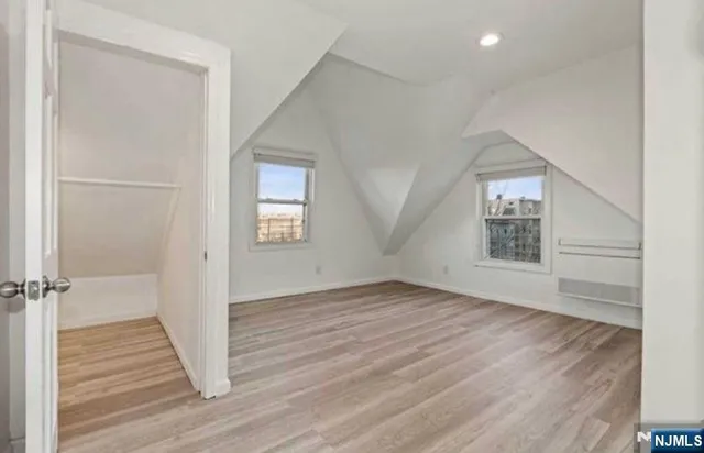 an empty room with wooden floor closet and windows