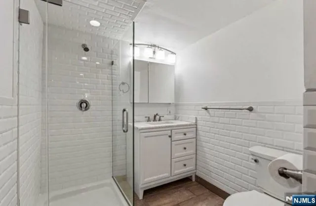 a bathroom with a granite countertop sink a toilet and shower