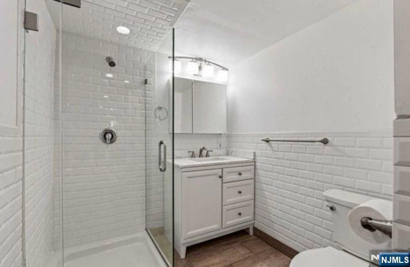 454 Undercliff Avenue Edgewater, NJ 07020 - Photo 15 of 18 a bathroom with a granite countertop sink a toilet and shower