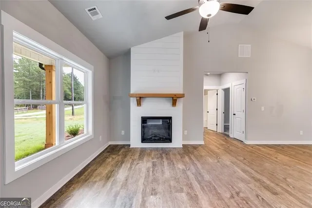 a view of an empty room with wooden floor fireplace and a window