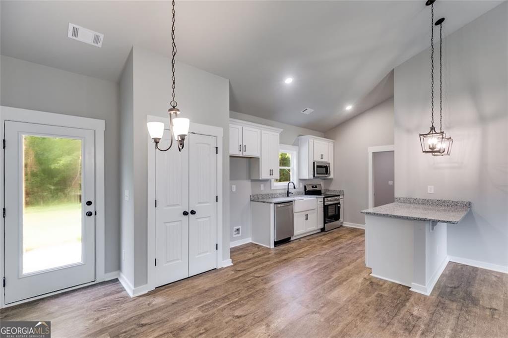 525 Grogan Road Buchanan, GA 30113 - Photo 25 of 40 a large kitchen with granite countertop a large counter top space stainless steel appliances and a chandelier