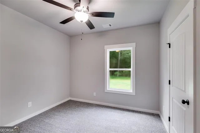an empty room with a window and a fan