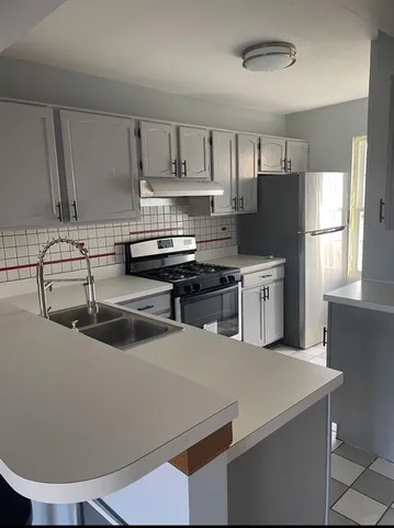 a kitchen with stainless steel appliances a sink a stove a refrigerator and cabinets