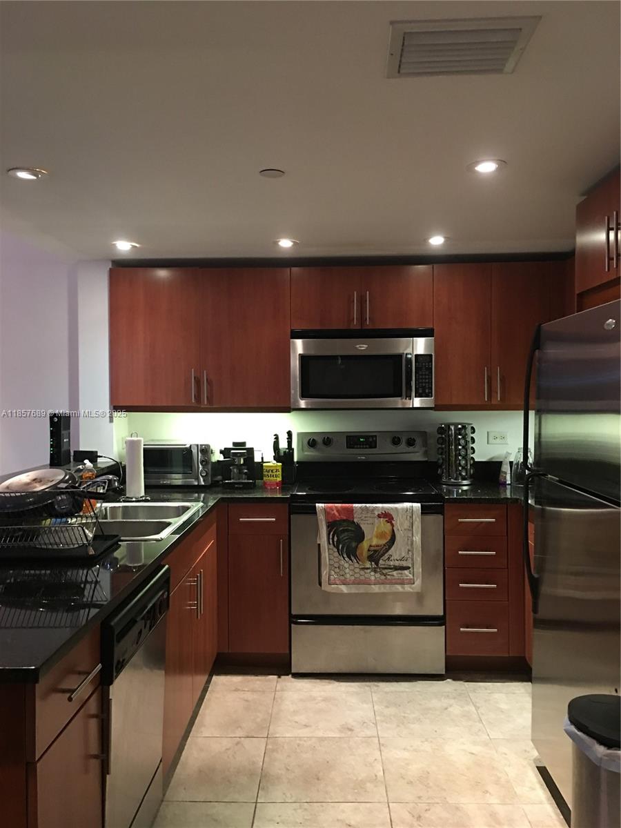 111 East Flagler Street, Unit 1007 Miami, FL 33131 - Photo 3 of 13 a kitchen with stainless steel appliances granite countertop wooden cabinets a stove top oven a sink and dishwasher