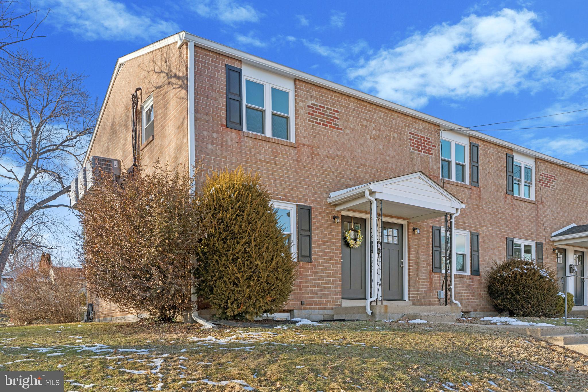 a view of a brick house with many windows and a tree