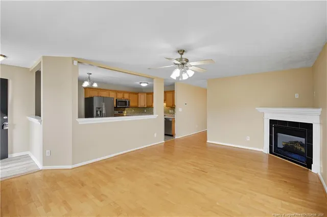a view of an empty room with chandelier and fire place