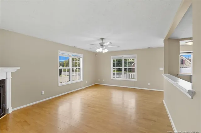 a view of an empty room with a window and wooden floor