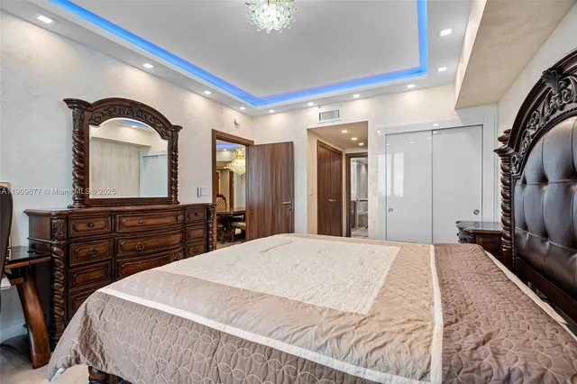 a large bedroom with a bed and a dresser with mirror