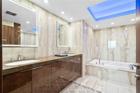 a bathroom with a double vanity sink large mirror and a bathtub
