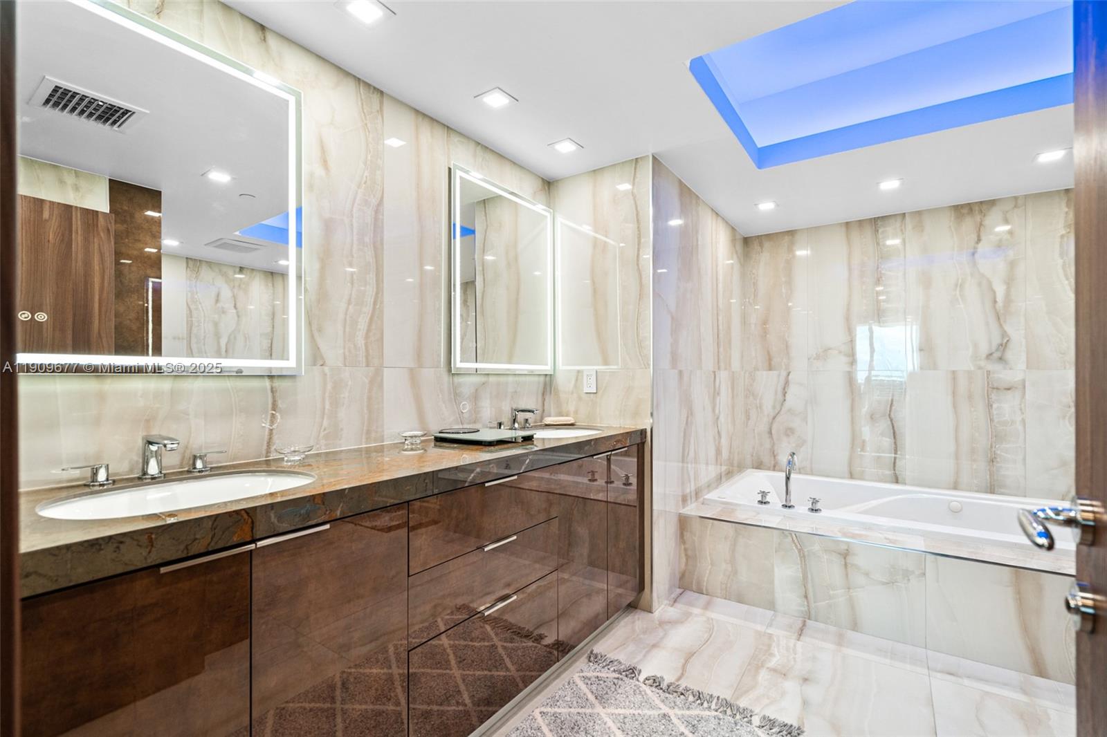 9559 Collins Avenue, Unit S8F Surfside, FL 33154 - Photo 16 of 27 a bathroom with a double vanity sink large mirror and a bathtub