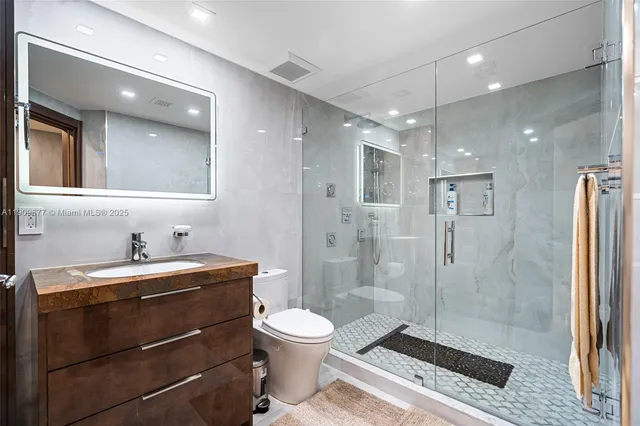 a bathroom with a shower a sink a toilet and a mirror