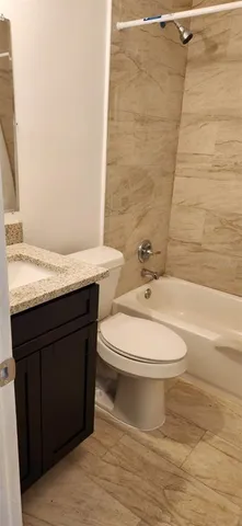 a bathroom with a granite countertop bathtub sink vanity mirror and toilet