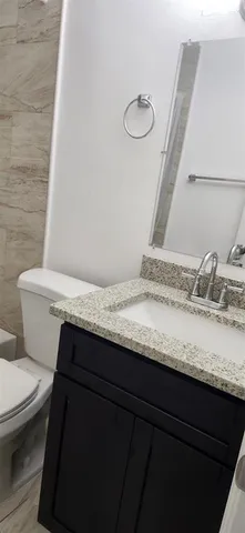 a bathroom with a granite countertop sink a toilet and a mirror