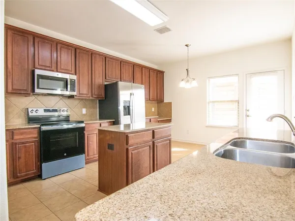 a kitchen with stainless steel appliances granite countertop a refrigerator a stove top oven a sink and dishwasher