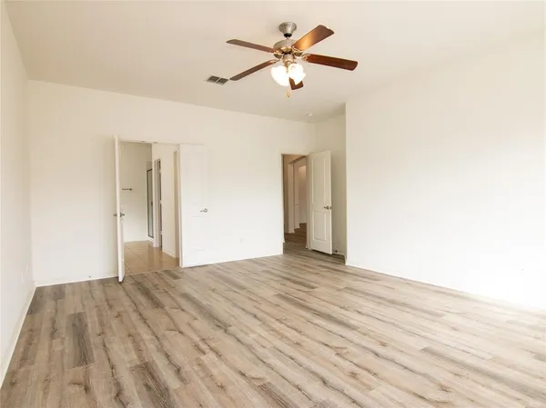 an empty room with wooden floor fan and windows