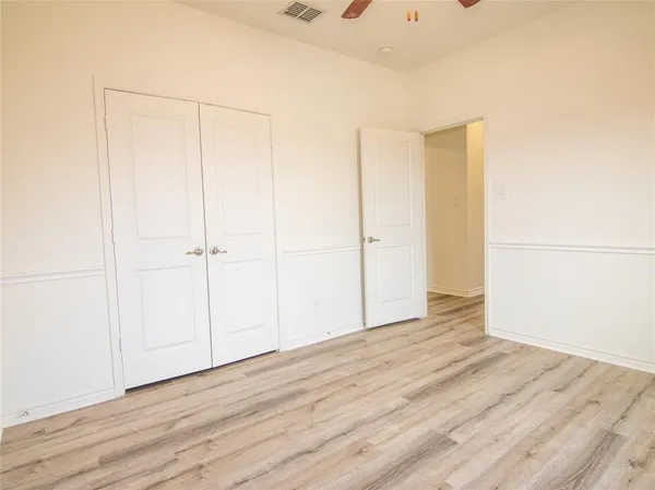 an empty room with wooden floor chandelier fan and windows