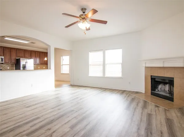 an empty room with wooden floor fireplace and windows