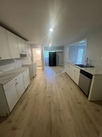 a large kitchen with a sink and dishwasher a stove top oven with wooden floor