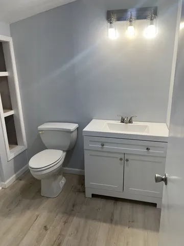 a bathroom with a toilet a sink a window and mirror