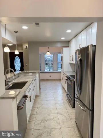 a kitchen with stainless steel appliances granite countertop a refrigerator a stove and a sink