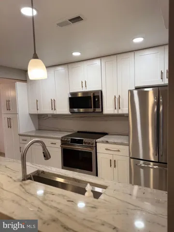 a kitchen with stainless steel appliances a stove a sink a refrigerator and a fireplace