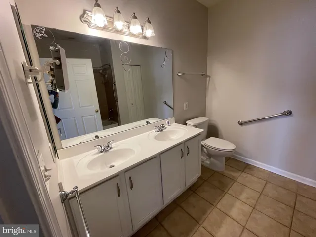 a bathroom with a double vanity sink mirror and toilet