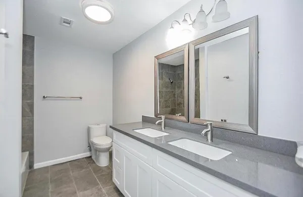 a bathroom with a granite countertop sink a toilet and a mirror