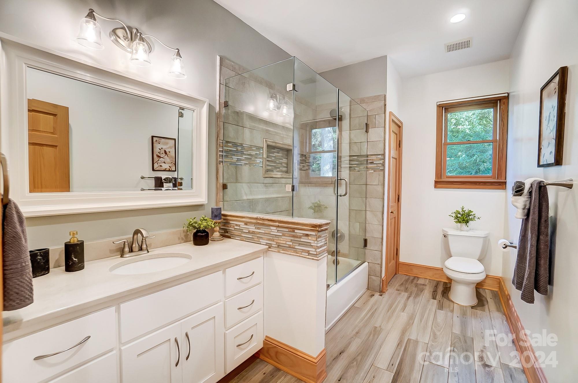 6338 Talley Road Stanfield, NC 28163 - Photo 20 of 48 a spacious bathroom with a granite countertop sink toilet a large mirror a bathtub and next to a window