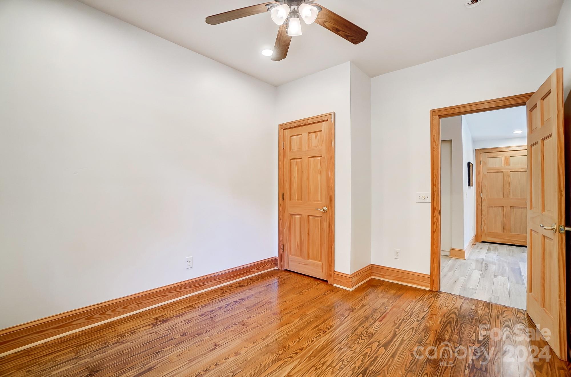 6338 Talley Road Stanfield, NC 28163 - Photo 24 of 48 an empty room with wooden floor chandelier fan and windows