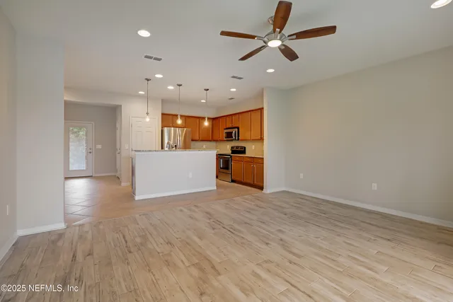a view of a big room with wooden floor and a kitchen