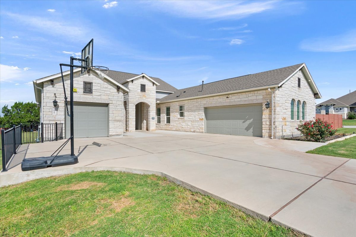 3625 Garrano Bend Leander, TX 78641 - Photo 34 of 38 A spacious driveway leads to this charming stone-clad residence with multiple garage bays.