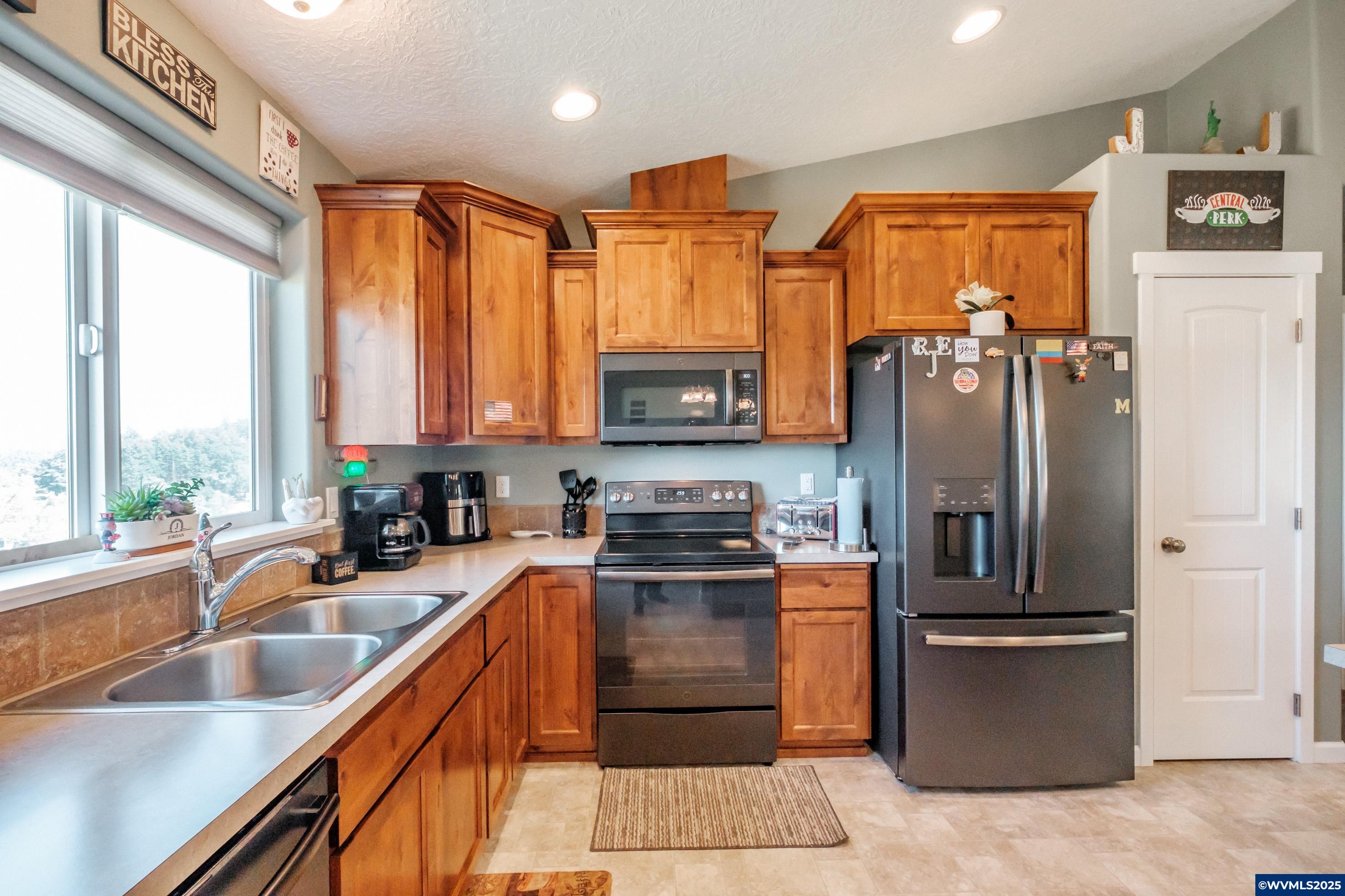 12433 Summit Loop Road Southeast Turner, OR 97392 - Photo 17 of 41 a kitchen with stainless steel appliances granite countertop a refrigerator a stove and a sink with wooden floors