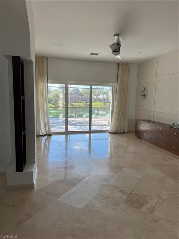 15890 Delasol Lane Naples, FL 34110 - Photo 10 of 16 an empty room with large windows and a ceiling fan