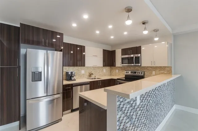 a kitchen with stainless steel appliances granite countertop a refrigerator and a stove top oven