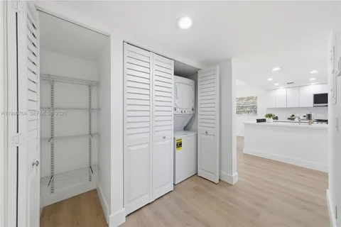 a view of a kitchen with wooden floor and white cabinets