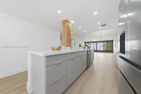 a large white kitchen with a sink and dishwasher a stove with wooden floor
