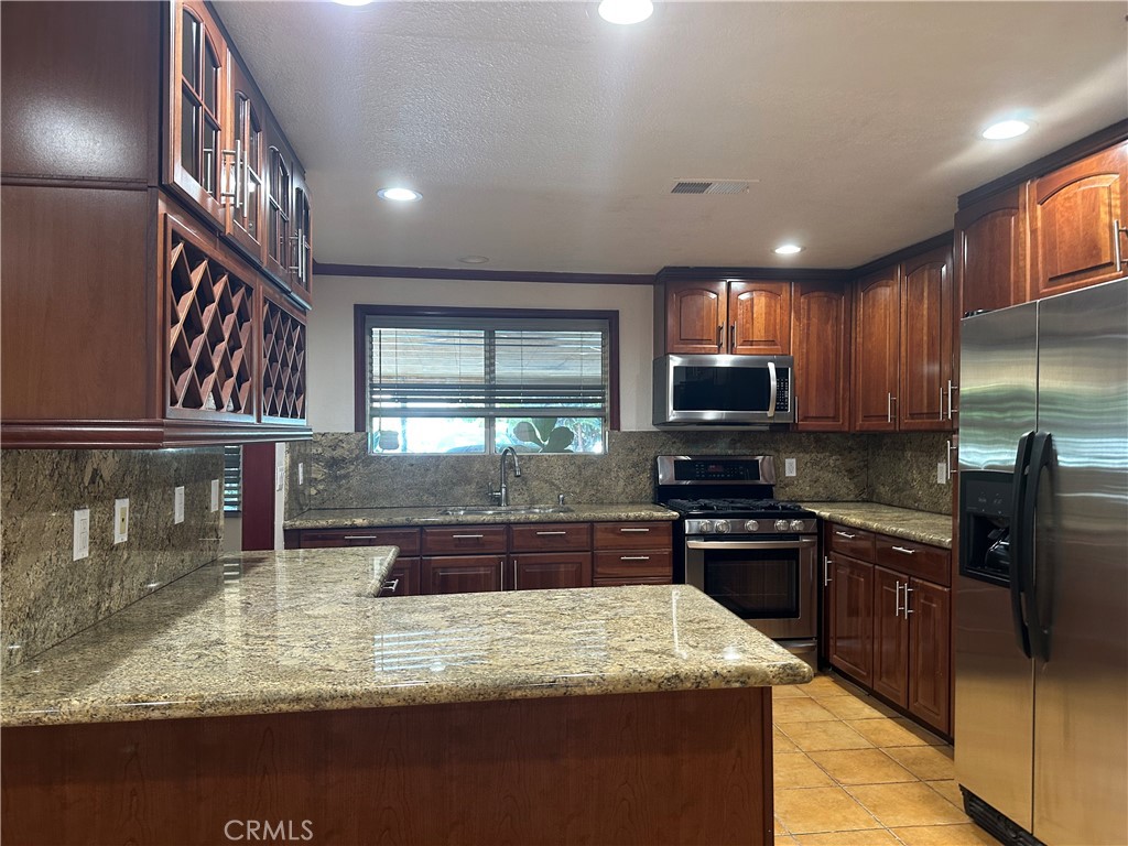 7721 Rhea Avenue Reseda, CA 91335 - Photo 11 of 16 a kitchen with stainless steel appliances granite countertop wooden cabinets a stove top oven a sink and dishwasher