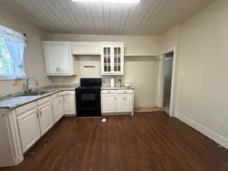 a kitchen with granite countertop a stove a sink dishwasher and a refrigerator with wooden floor