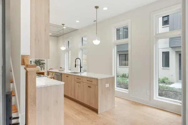 a large white kitchen with a sink large window and stainless steel appliances