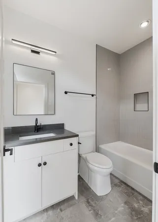 a bathroom with a granite countertop toilet a sink and a mirror