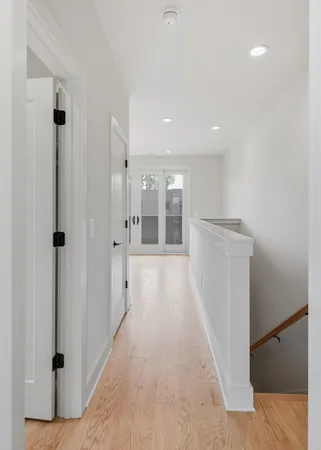 a view of a hallway with wooden floor and a bathroom