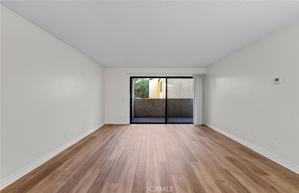 600 West 3rd Street, Unit 107 Santa Ana, CA 92701 - Photo 3 of 26 an empty room with wooden floor and glass door