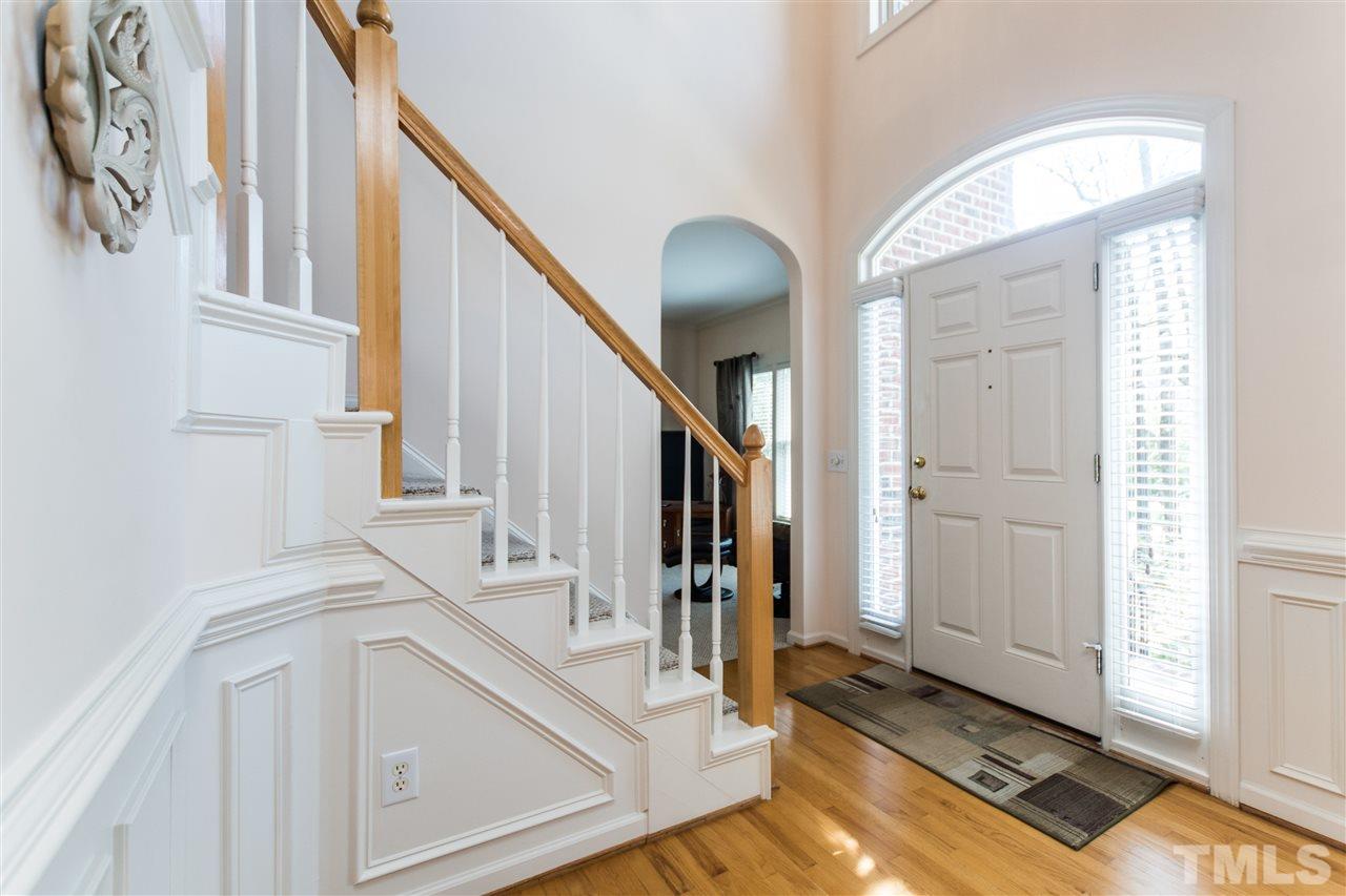 Two-Story Foyer with Open Staircase lead into Formal Dining Room with Hardwoods and Wainscotting