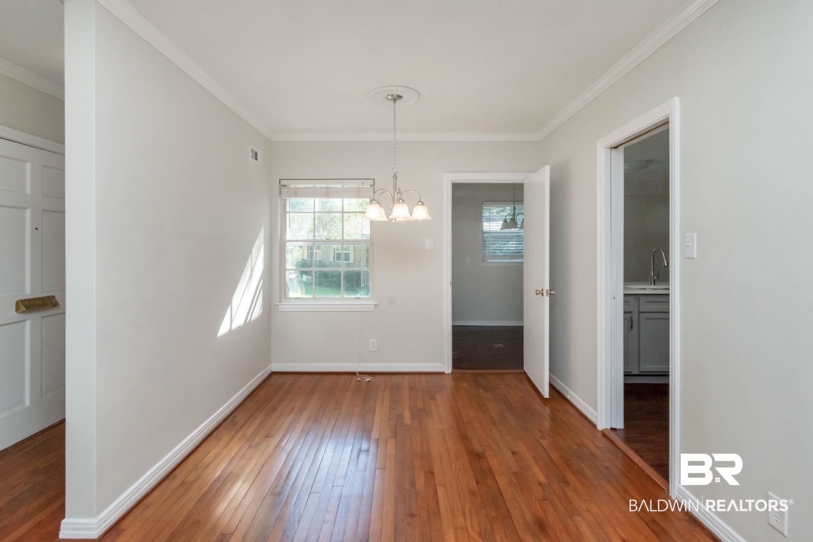 2105 Upham Court Mobile, AL 36607 - Photo 10 of 32 Unfurnished dining area featuring hardwood / wood-style flooring, ornamental molding, and a chandelier