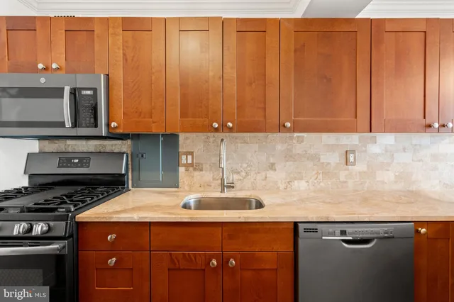 a kitchen with stainless steel appliances granite countertop a sink a stove a microwave cabinets and a counter top space