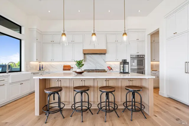 a kitchen with stainless steel appliances granite countertop a table chairs sink and wooden floor