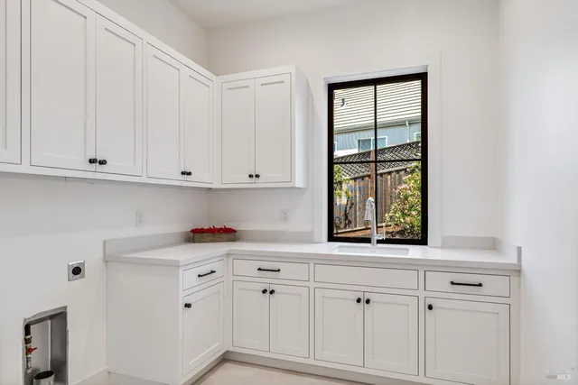 a kitchen with white cabinets and window