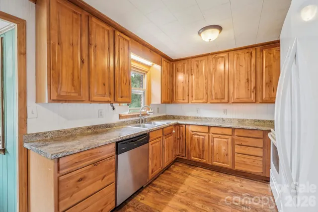 a kitchen with stainless steel appliances granite countertop wooden cabinets a sink and dishwasher with wooden floor