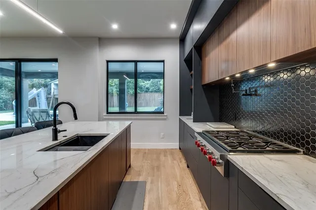 a kitchen with stainless steel appliances kitchen island a table chairs in it and wooden floors