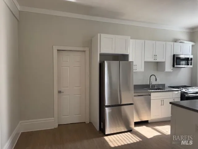 a kitchen with stainless steel appliances granite countertop a refrigerator a stove a sink and white cabinets